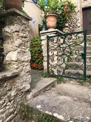 a garden gate with a flower pot on a stone wall at Charmante maison de village à Fontaine-de-Vaucluse in Fontaine-de-Vaucluse