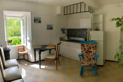 a kitchen with a table and chairs and a refrigerator at Charmante maison de village à Fontaine-de-Vaucluse in Fontaine-de-Vaucluse