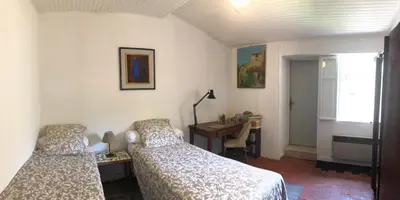 a bedroom with two beds and a desk and a window at Charmante maison de village à Fontaine-de-Vaucluse in Fontaine-de-Vaucluse