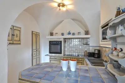 a kitchen with a table with two white stools at Domaine de la Marie dans le Luberon in Peypin-dʼAigues