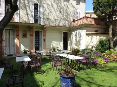 an outdoor patio with tables and chairs in front of a building at Hôtel du Fiacre in Carpentras