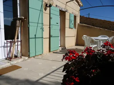 a patio with two white chairs and red flowers at Le Jas de Verdolier in Sault-de-Vaucluse