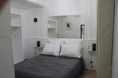 a bedroom with a bed with white walls and a mirror at Le Mas des Chênes in Rognes