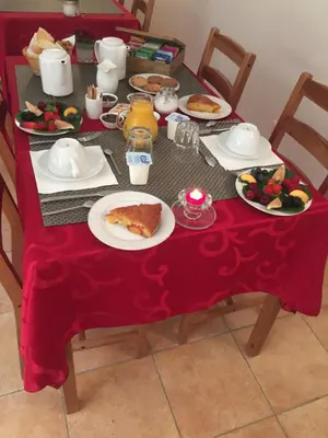 a table with plates of food on a red table cloth at Le Mas des Chênes in Rognes