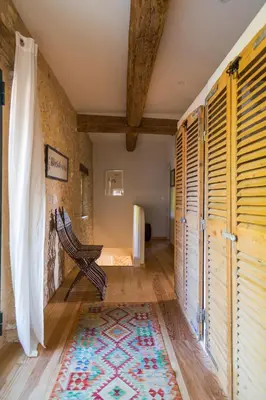a room with wooden shutters and a rug at Le Mas de la Sorgue in Le Thor