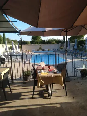 a table and chairs under an umbrella next to a pool at Mas Dansavan Chambres d'hôtes in Oppède