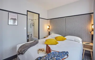 a hotel room with a large bed with yellow pillows at Appart'hôtel Odalys City - Aix en Provence Centre Palais des Congrès in Aix-en-Provence
