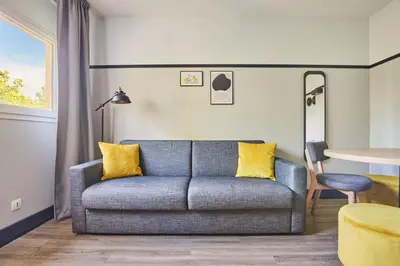 a living room with a couch and a table at Appart'hôtel Odalys City - Aix en Provence Centre Palais des Congrès in Aix-en-Provence