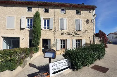 a large stone building with a sign in front of it at Le Cheval Blanc in La Bastide-des-Jourdans