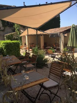 an outdoor patio with tables and an umbrella at Le Cheval Blanc in La Bastide-des-Jourdans