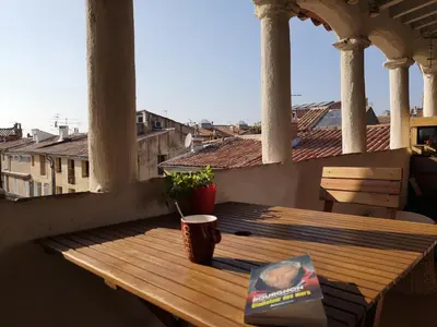 a wooden table on a balcony with a book at Toits Vieil Aix - Appartement de charme avec terrasse d'exception centre ville historique proche Cardeurs Et Mairie in Aix-en-Provence