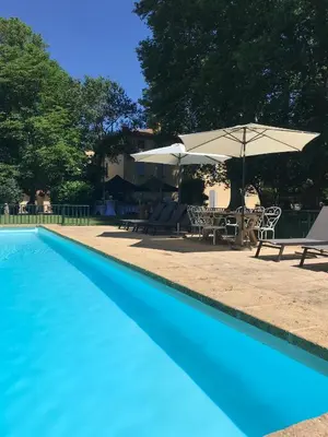 a blue swimming pool with a table and an umbrella at Château de Saint-Girons - Luxury Guest House in Provence in Aix-en-Provence