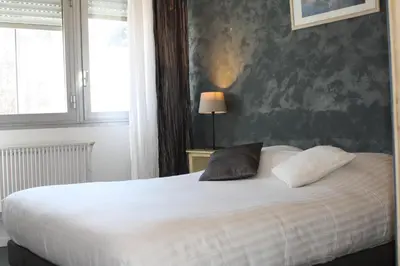 a bedroom with a bed with two pillows on it at Hotel du Midi in Salon-de-Provence