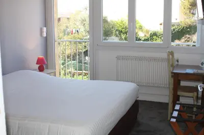 a bedroom with a white bed and two windows at Hotel du Midi in Salon-de-Provence