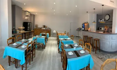 a restaurant with blue tables and chairs and a counter at Hotel du Midi in Salon-de-Provence