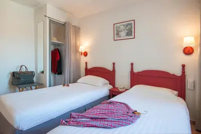 a bedroom with two beds and a robe laying on the bed at Hotel du Forum in Carpentras
