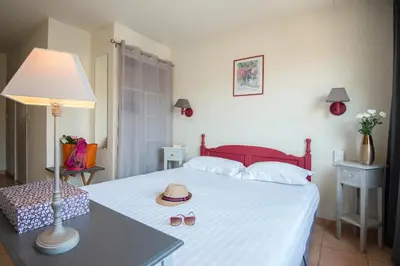 a bedroom with a bed with a hat and slippers on it at Hotel du Forum in Carpentras