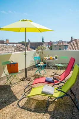a group of chairs and an umbrella on a roof at Hotel du Forum in Carpentras