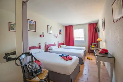 a hotel room with two beds and a table at Hotel du Forum in Carpentras