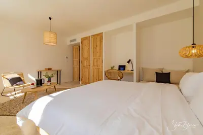 a white bedroom with a large bed and a chair at Moulin de la Roque in Althen-des-Paluds