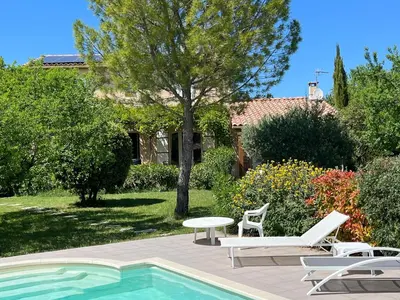 a pool with two chairs and a table next to a house at L'Atelier de Maia in Mormoiron