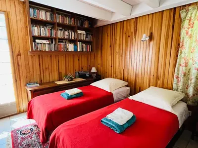 two red beds in a room with a book shelf at L'Atelier de Maia in Mormoiron