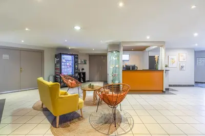 a lobby with two yellow chairs and a table at Appart'City Classic Aix-en-Provence - La Duranne in Aix-en-Provence