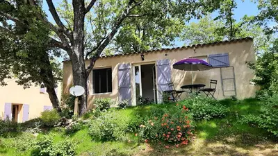 a house with a table and an umbrella at Le Cabanon in Sainte-Croix-à-Lauze