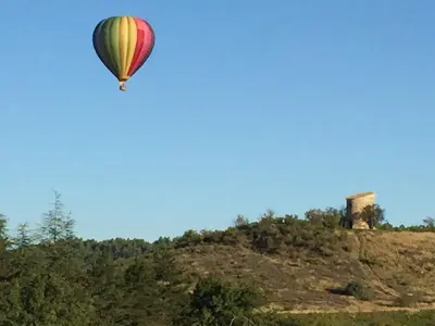 a hot air balloon in the sky over a hill at Logis Hôtel Le Manoir - Luberon in Apt