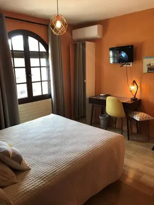 a bedroom with a bed and a desk and a window at Logis Hôtel Le Manoir - Luberon in Apt