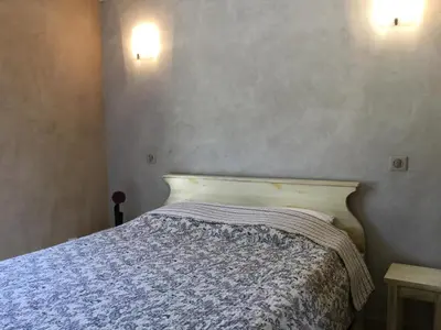 a bed in a bedroom with two lights on the wall at typical provencal bastide, built of local stones, in the luberon in cheval-blanc with secured pool and wifi -sleeps 6 people. in Cheval-Blanc