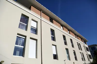 a white building with windows on the side at Résidence Les Académies Aixoise in Aix-en-Provence