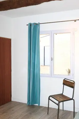 a chair in front of a window with a blue curtain at ROGERIO en PLEIN CENTRE DE L'ISLE SUR SORGUE in LʼIsle-sur-la-Sorgue