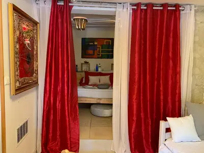 a room with red curtains and a bedroom with a bed at DEPENDANCE PRIVEE - HALTE ROUTE in Le Thor