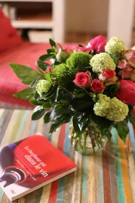 a vase of flowers on a table next to a book at DOMAINE de MAS CARON Gîte 4* au pied du Ventoux en Provence in Caromb