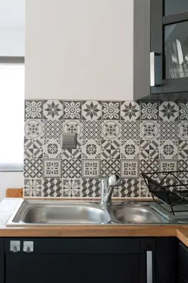 a kitchen with a sink and a tile wall at Gîte du Charme Provençal in Sénas