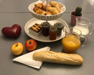 a table with a plate of bread and apples and a basket of bread at Une Pause Douceur - Suite Orchidée in Eyguières