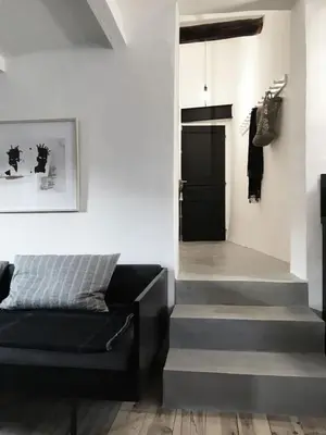 a living room with a staircase and a black couch at La Magnanerie in LʼIsle-sur-la-Sorgue