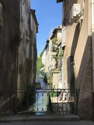 an alley with a river between two buildings at La Magnanerie in LʼIsle-sur-la-Sorgue