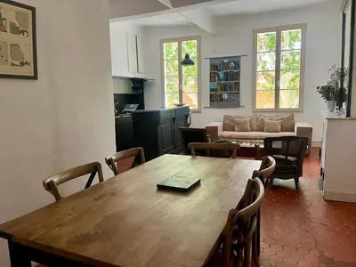 a kitchen and living room with a wooden table and chairs at Beau 3 pièces 83 m2 au coeur du centre historique d'Aix en Provence in Aix-en-Provence
