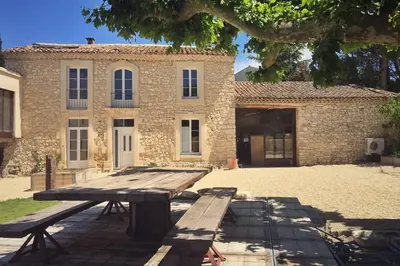 a wooden picnic table in front of a brick building at Mas de L Angeos in Velleron