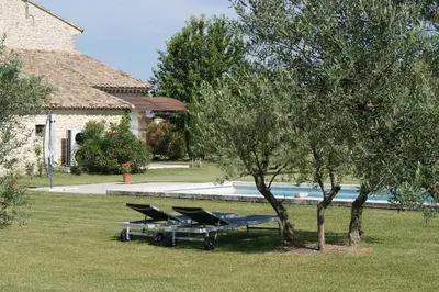 a group of picnic tables next to a swimming pool at B&B dans Mas en pierres in Robion en Luberon