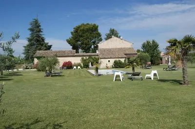 a house with a yard with white chairs in the grass at B&B dans Mas en pierres in Robion en Luberon