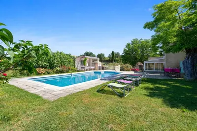 a swimming pool in a yard with two lawn chairs at Villa charmante à La Tour-d'Aigues avec piscine privée in La Tour-dʼAigues