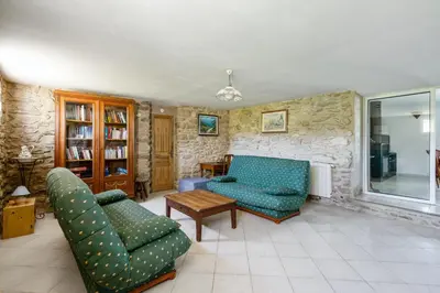 a living room with two couches and a stone wall at Villa charmante à La Tour-d'Aigues avec piscine privée in La Tour-dʼAigues
