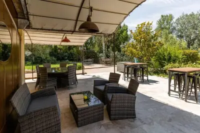 a patio with tables and chairs and an umbrella at La Bastide de l Etang in LʼIsle-sur-la-Sorgue