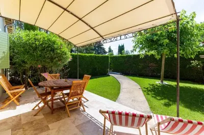 a patio with a table and chairs under an umbrella at La Bastide de l Etang in LʼIsle-sur-la-Sorgue