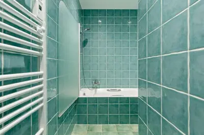 a bathroom with green tiled walls and a bath tub at La Bastide de l Etang in LʼIsle-sur-la-Sorgue