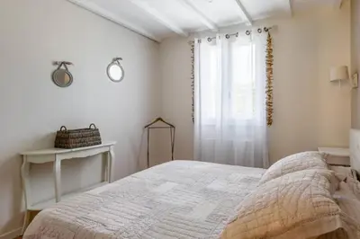a white bedroom with a bed and a window at La Bastide de l Etang in LʼIsle-sur-la-Sorgue