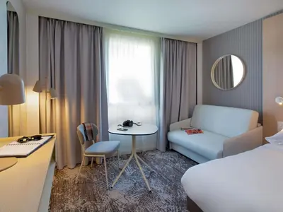 a hotel room with a bed and a table and a chair at Novotel Aix-en-Provence Pont de L'Arc in Aix-en-Provence